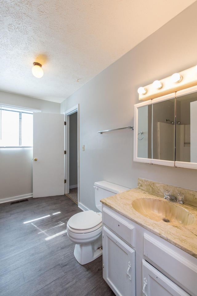 bathroom with vanity, wood finished floors, visible vents, a textured ceiling, and toilet