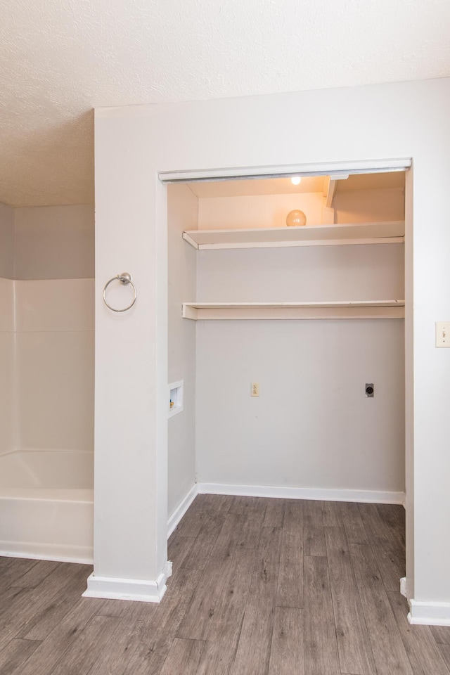 laundry room featuring wood finished floors, baseboards, laundry area, electric dryer hookup, and a textured ceiling