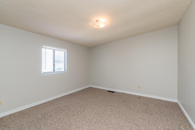 spare room featuring carpet flooring, baseboards, and visible vents