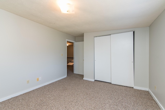 unfurnished bedroom with carpet flooring, baseboards, and a closet