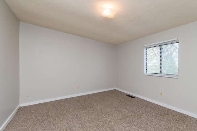 carpeted empty room with visible vents, a textured ceiling, and baseboards