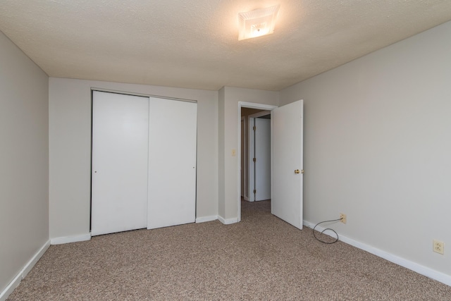 unfurnished bedroom with a closet, baseboards, carpet, and a textured ceiling