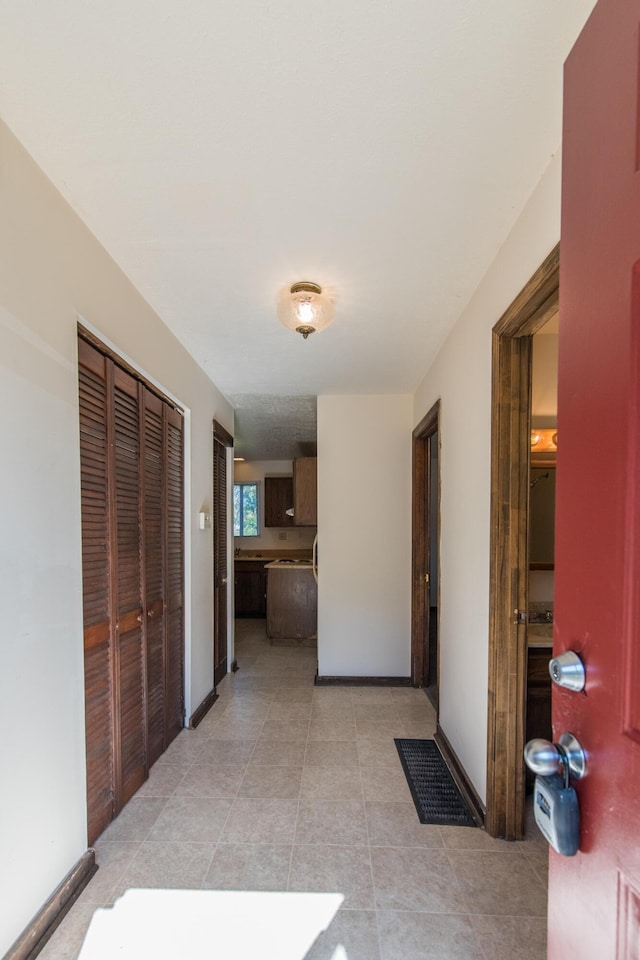 corridor with light tile patterned floors and baseboards