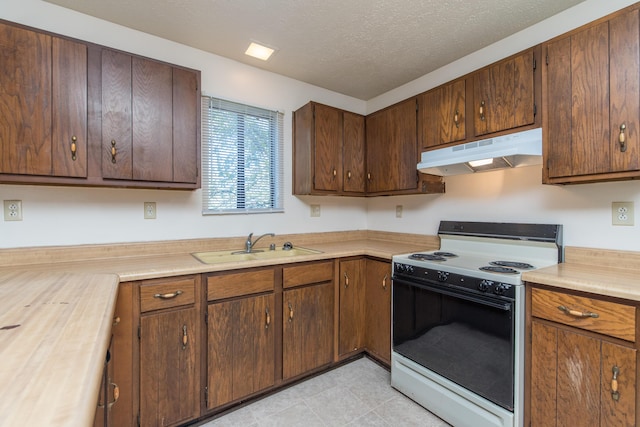 kitchen with a sink, electric range oven, light countertops, under cabinet range hood, and a textured ceiling