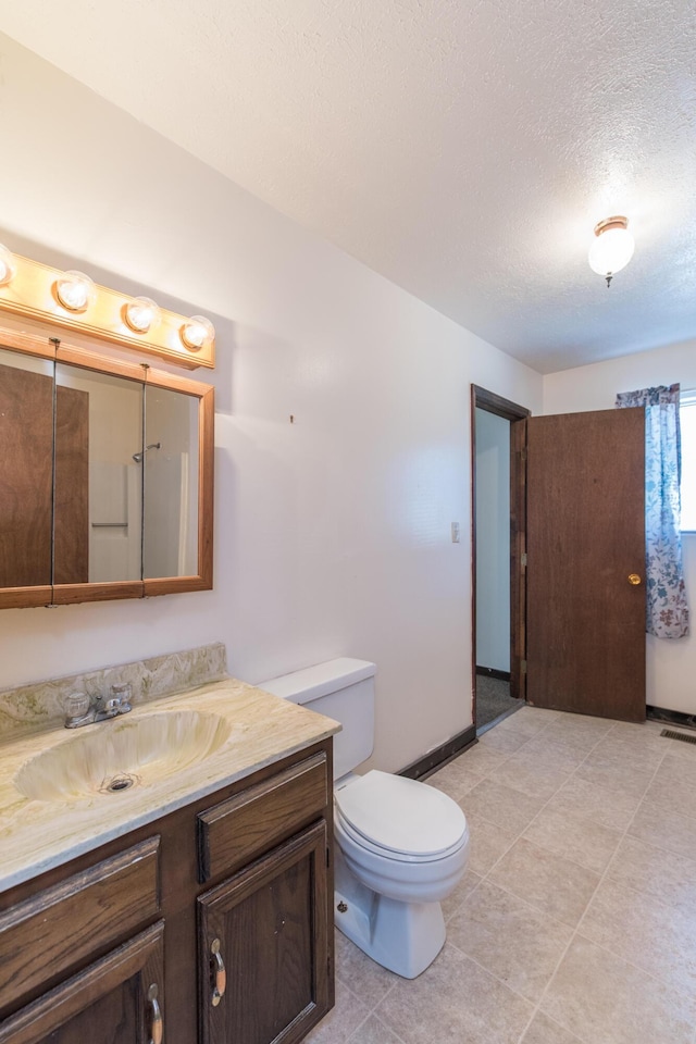 bathroom with vanity, baseboards, tile patterned flooring, a textured ceiling, and toilet