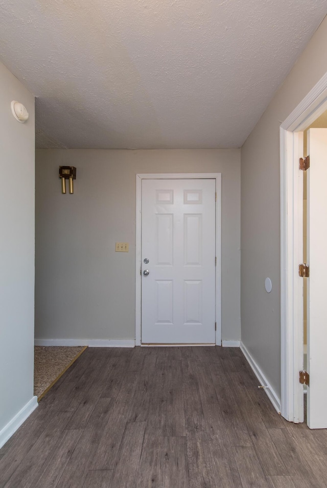 interior space featuring a textured ceiling, baseboards, and dark wood-style flooring