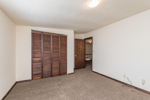 unfurnished bedroom featuring a closet, baseboards, carpet, and a textured ceiling