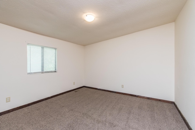 unfurnished room with a textured ceiling, baseboards, and carpet floors