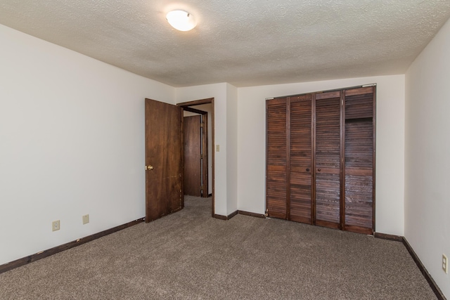 unfurnished bedroom with a closet, a textured ceiling, baseboards, and carpet