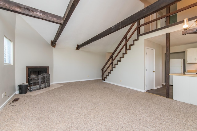 unfurnished living room with dark colored carpet, a fireplace with flush hearth, lofted ceiling with beams, and stairs