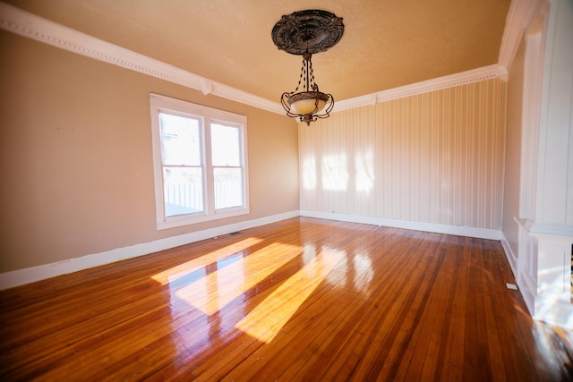 unfurnished room with wood-type flooring, baseboards, and ornamental molding