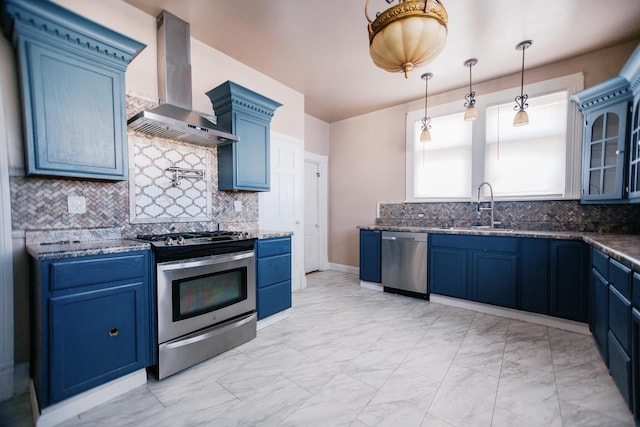 kitchen with marble finish floor, a sink, blue cabinetry, appliances with stainless steel finishes, and wall chimney range hood