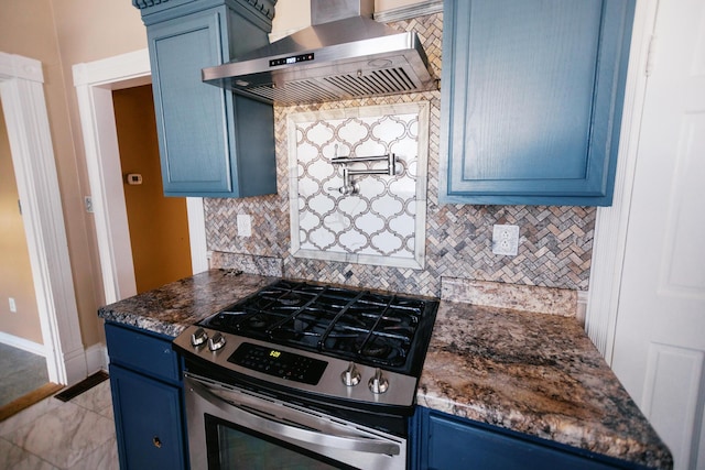 kitchen with tasteful backsplash, blue cabinetry, dark stone counters, stainless steel gas stove, and wall chimney exhaust hood