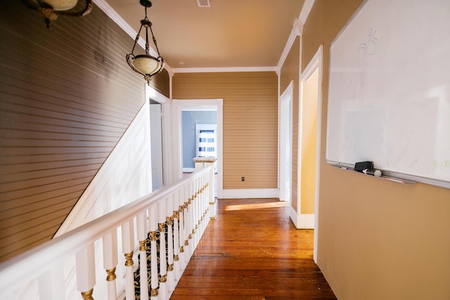 hallway featuring visible vents, wood-type flooring, baseboards, and ornamental molding