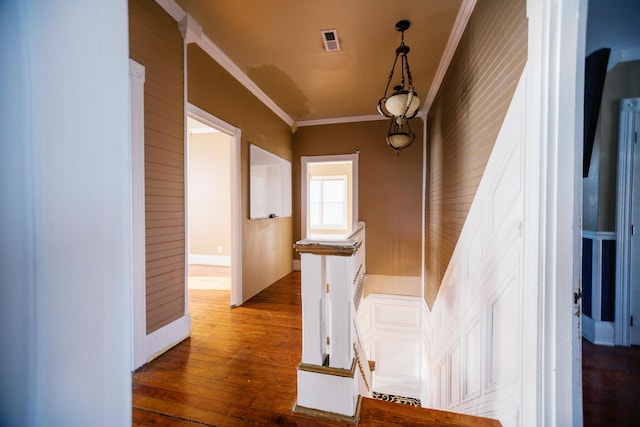 stairs with visible vents, wood finished floors, and crown molding