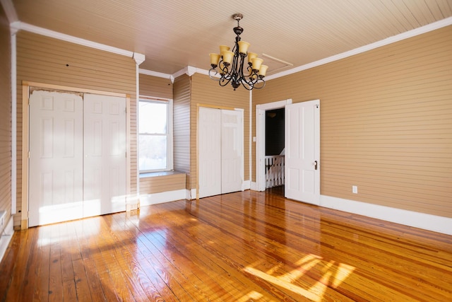 interior space featuring hardwood / wood-style floors, ornamental molding, baseboards, and a chandelier