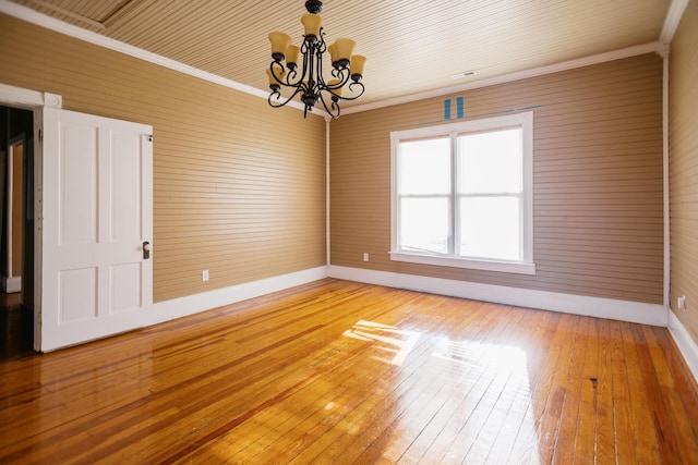 spare room featuring baseboards, light wood-style floors, an inviting chandelier, and ornamental molding