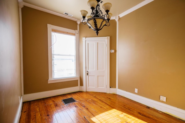 unfurnished room featuring a notable chandelier, crown molding, visible vents, and hardwood / wood-style flooring