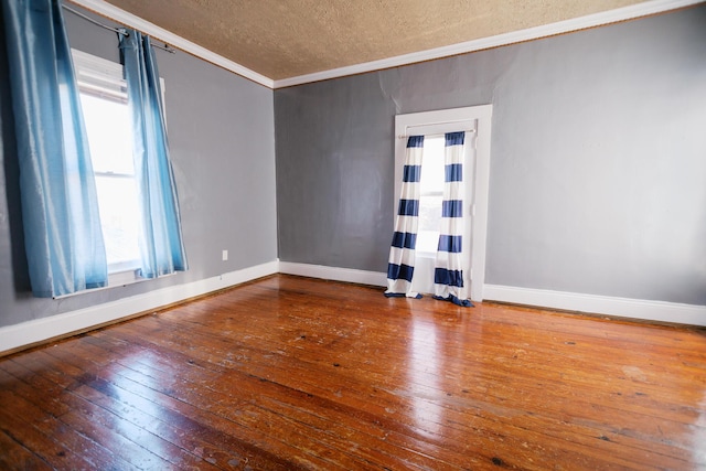 empty room featuring ornamental molding, a textured ceiling, baseboards, and hardwood / wood-style floors