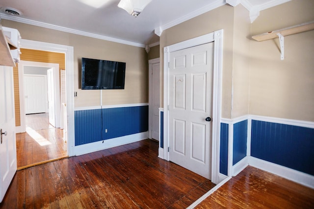 unfurnished bedroom with visible vents, wood-type flooring, ornamental molding, and wainscoting