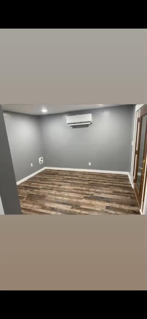 interior space with wood finished floors, baseboards, and a wall mounted air conditioner