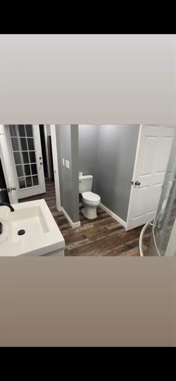 bathroom featuring toilet, wood finished floors, and baseboards