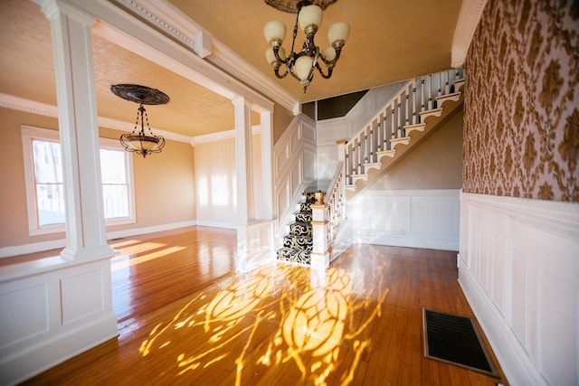 interior space featuring a decorative wall, visible vents, ornate columns, and a chandelier