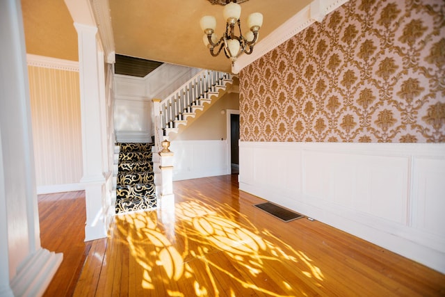 interior space featuring visible vents, wallpapered walls, stairway, hardwood / wood-style flooring, and a notable chandelier