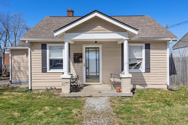 bungalow with a shingled roof, a chimney, a front lawn, and fence