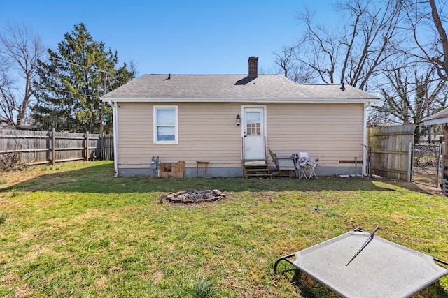 rear view of house with entry steps, a yard, a fenced backyard, and a chimney