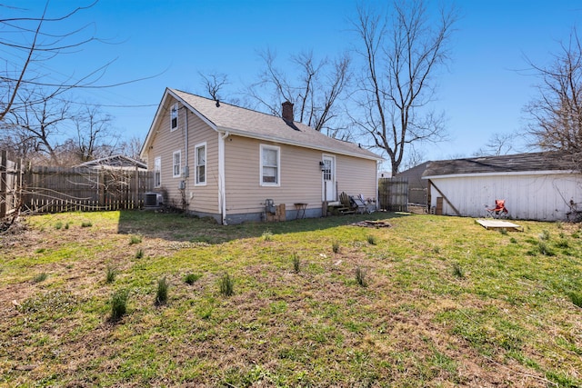 back of property featuring a yard, a fenced backyard, central AC, a chimney, and entry steps