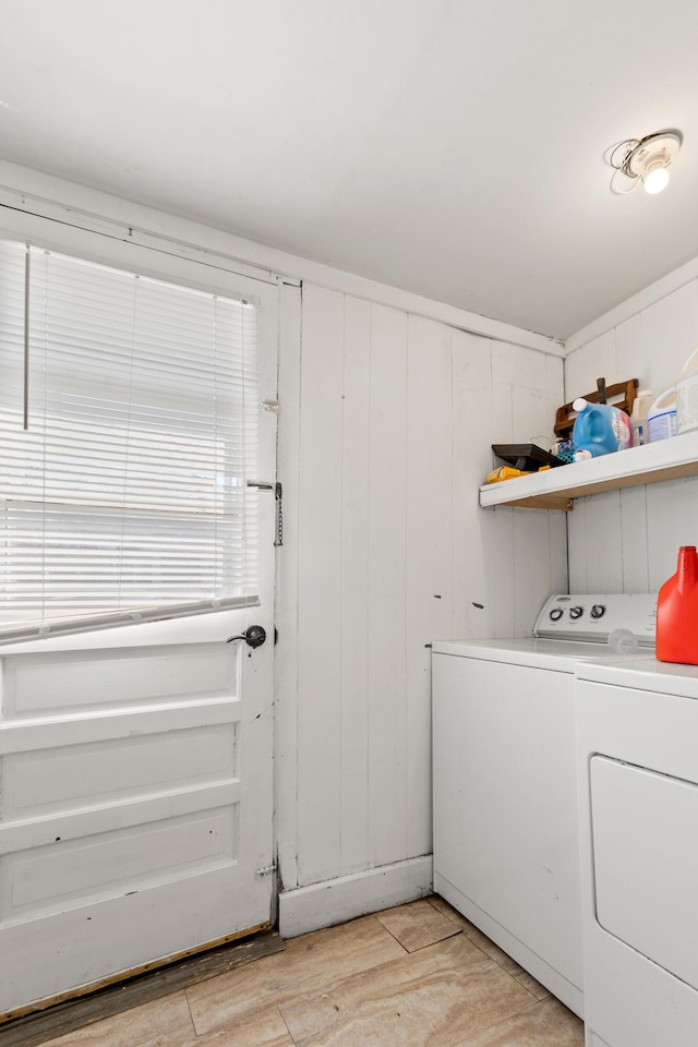 clothes washing area with light wood finished floors, laundry area, and washing machine and dryer