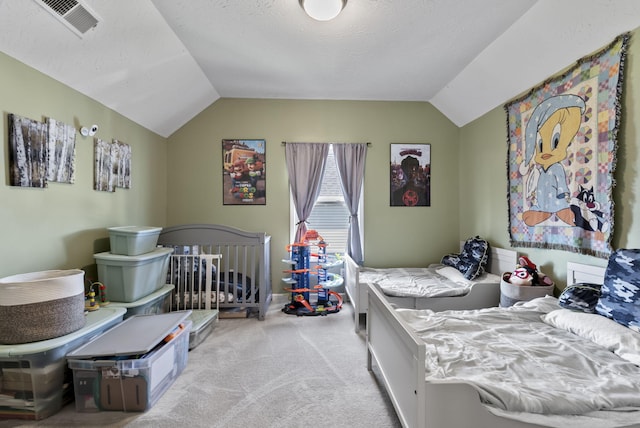 bedroom with vaulted ceiling, carpet, visible vents, and a textured ceiling