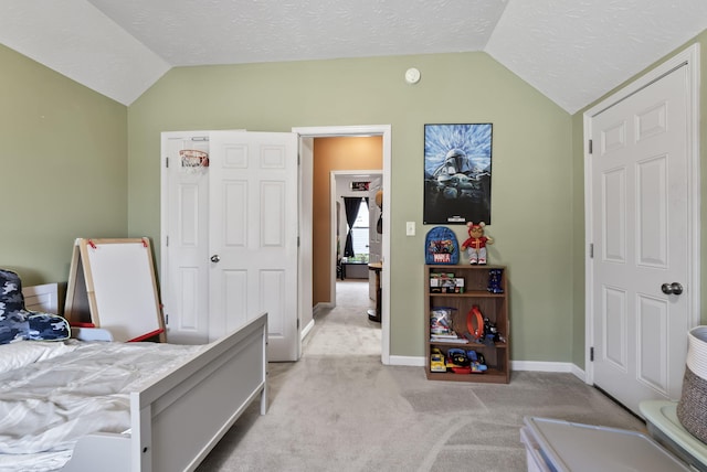 bedroom with a textured ceiling, baseboards, light colored carpet, and vaulted ceiling