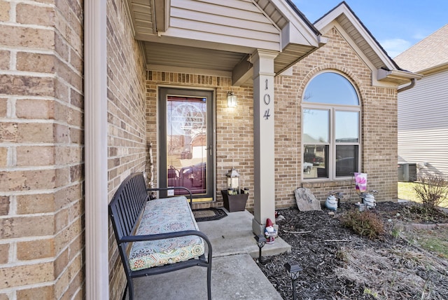 doorway to property featuring brick siding and cooling unit