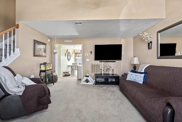 carpeted living room with visible vents, a textured ceiling, and stairs