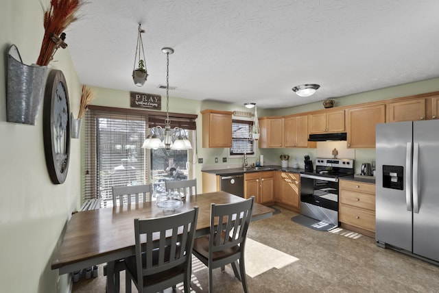 kitchen featuring under cabinet range hood, a sink, dark countertops, appliances with stainless steel finishes, and a chandelier