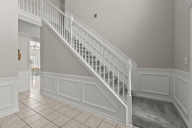 stairs with visible vents, carpet floors, tile patterned flooring, and a decorative wall