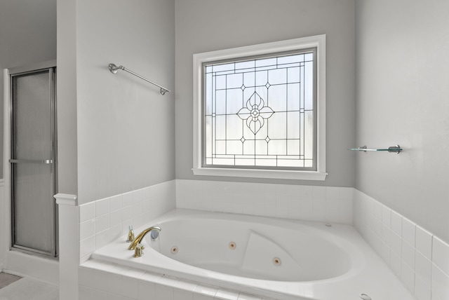 bathroom featuring a tub with jets and a shower stall