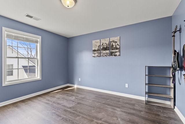 spare room with visible vents, baseboards, and wood finished floors