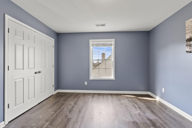 unfurnished bedroom featuring visible vents, baseboards, and wood finished floors