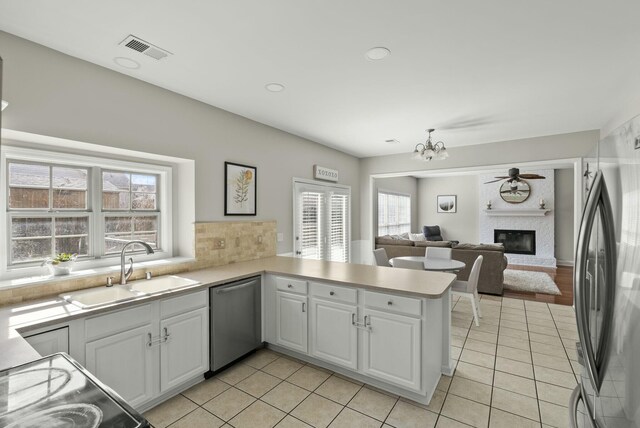 kitchen featuring visible vents, light tile patterned floors, a glass covered fireplace, stainless steel appliances, and a sink