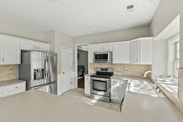 kitchen featuring visible vents, a sink, stainless steel appliances, white cabinetry, and tasteful backsplash