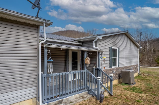 entrance to property with central air condition unit, covered porch, and metal roof