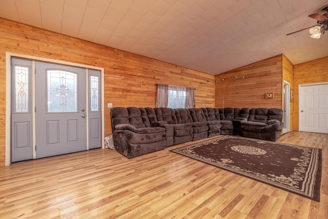 living room with vaulted ceiling, wood walls, plenty of natural light, and wood finished floors