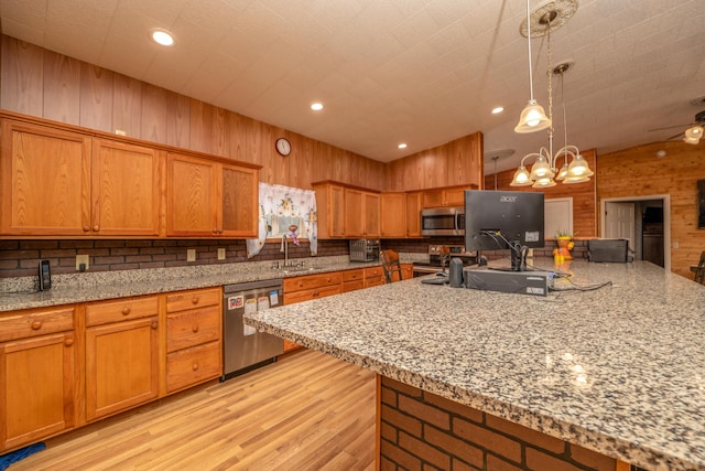 kitchen featuring a sink, light wood-style floors, wood walls, appliances with stainless steel finishes, and brown cabinets