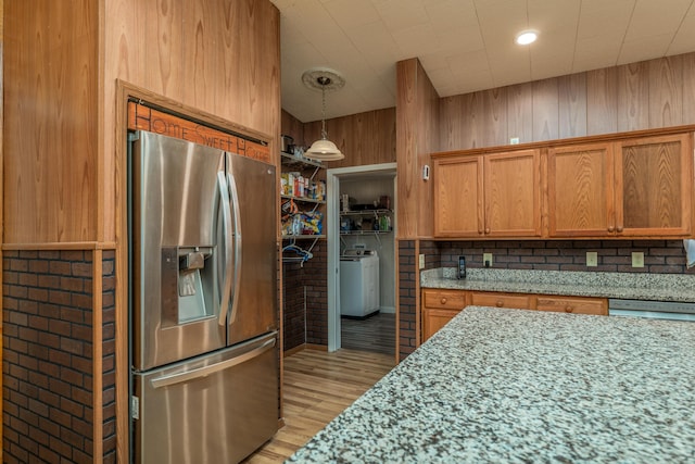 kitchen with washer / dryer, stainless steel fridge, light wood-type flooring, and brown cabinets