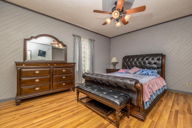 bedroom featuring crown molding, light wood-style floors, baseboards, and ceiling fan