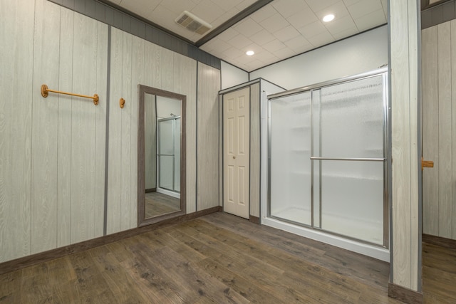 full bathroom featuring visible vents, a shower stall, wooden walls, and wood finished floors