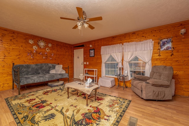 living area with a textured ceiling, ceiling fan, and light wood finished floors